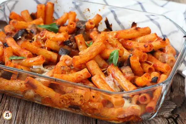 Piatto fumante di pasta alla siciliana in teglia, con melanzane, pomodoro e formaggio filante.