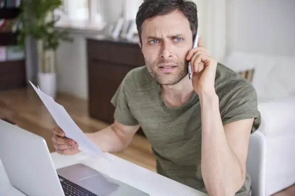 Zmartwiony mężczyzna trzyma dokumenty, rozmawiając przez telefon. Czyżby szykował apelację?