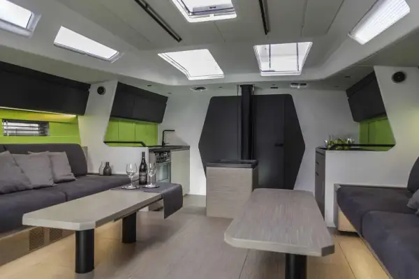 Interni moderni di una nave, con divani, tavoli, cucina e oblò sul soffitto.