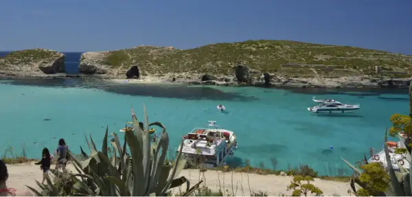 Malta co warto zobaczyć: Błękitna Laguna na Comino, z krystalicznie czystą wodą, łodziami i skalistymi klifami. Idealne miejsce na relaks.