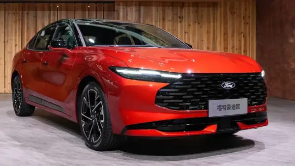 Nowy, lśniący, czerwony Ford Mondeo MK5 z czarnym dachem i felgami prezentuje się elegancko na tle drewnianej ściany.
