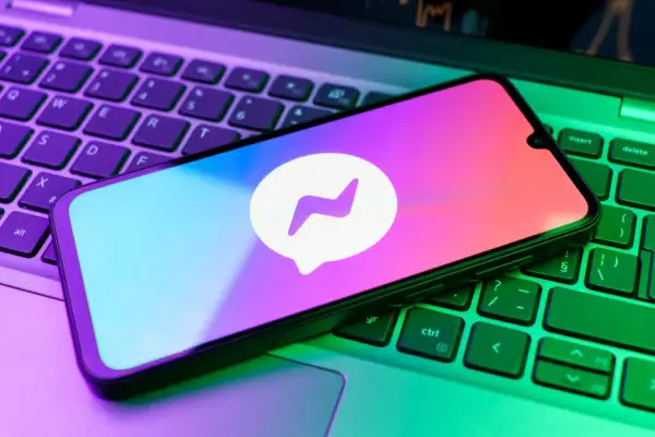Smartfon z logo Messengera na klawiaturze laptopa. Chcesz wiedzieć, jak zrobic aktualizacje Messengera?
