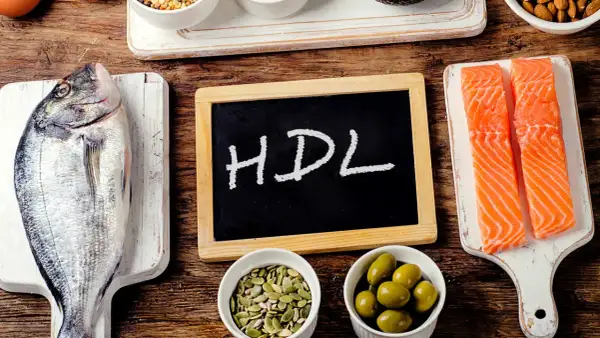 Ryba, łosoś, oliwki, pestki i tabliczka z napisem HDL na drewnianym tle.