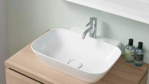 Lavabo blanc moderne sur meuble en bois, robinetterie chromée. La hauteur du lave-main wc est idéale pour un usage confortable.