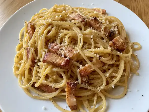 En portion riktig carbonara med spaghetti, knaprigt sidfläsk och rikligt med parmesanost.