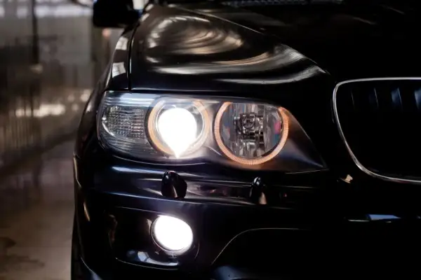 Gros plan sur les feux de position couleur d'une voiture noire, illuminant la nuit.