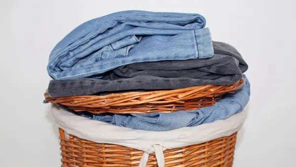 Ein Wäschekorb voller Jeans. Die oberste Jeans stinkt nach Chemie, ein deutliches Zeichen für eine neue Wäsche.
