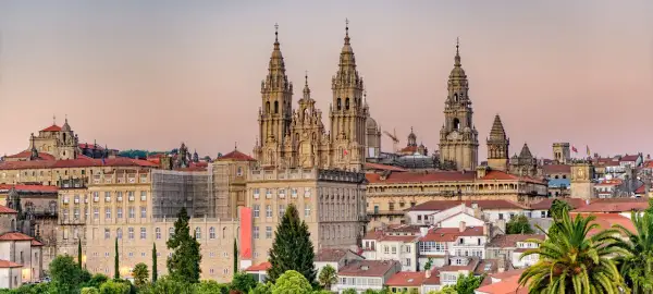 Majestatyczna katedra w Santiago de Compostela góruje nad miastem. W tle widać budynki i palmy.
