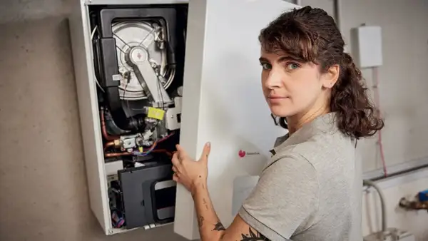 Une technicienne installe une chaudière F28. Elle tient le panneau avant ouvert, révélant les composants internes.