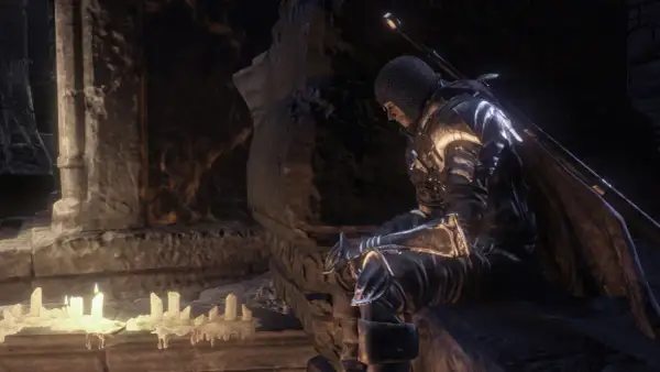 Rycerz w zbroi siedzi przy świecach, szukając wskazówek w **Dark Souls 3 poradnik**.