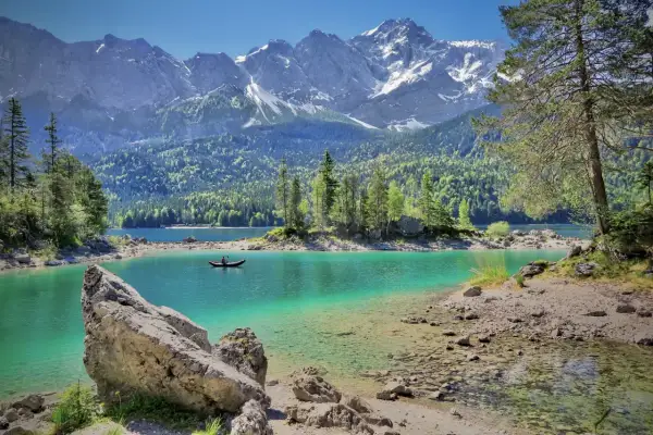 Türkisblaue Bergseen und schneebedeckte Gipfel – das sind die Attraktionen Bayerns. Ein Kajakfahrer gleitet über das klare Wasser.