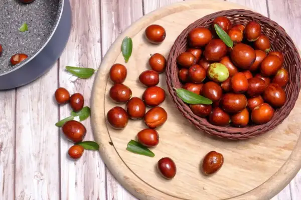 Giuggiole rosse e verdi in un cesto e sparse su un tagliere. Scopri quante calorie hanno le giuggiole per uno snack salutare.