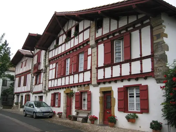 Maison basque typique, peut-être l'origine du nom Ithurburu. Volets rouges, colombages blancs, une voiture garée.