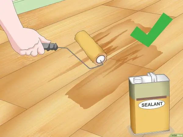 Application d'un scellant sur un plancher en bois. Le rouleau laisse une trace humide, signe que le produit pénètre bien le bois, éliminant toute rayure.