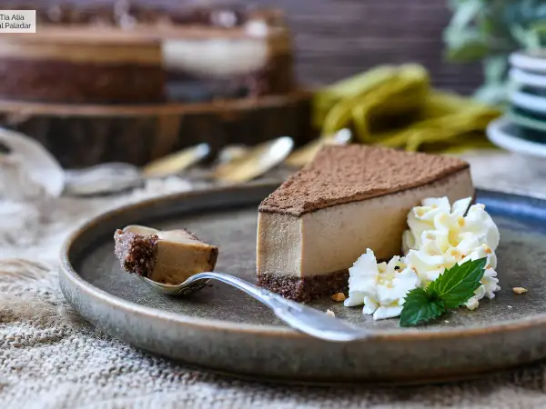 Deliciosa tarta de café con queso Philadelphia, cubierta de cacao y acompañada de nata montada y menta.