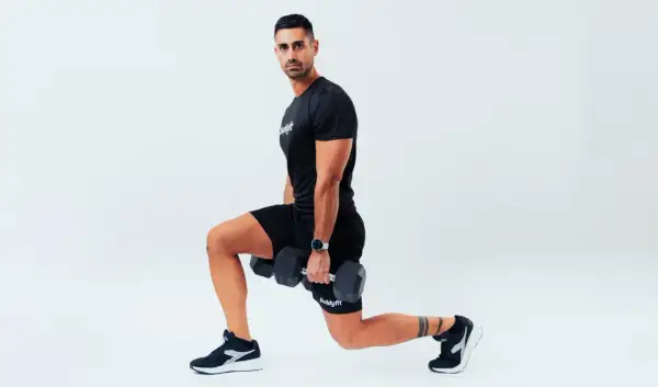 Uomo con manubri esegue affondi, un esercizio che rientra nel concetto di amrap significato: "as many reps as possible".