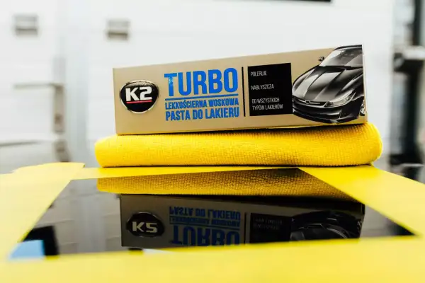 K2 Turbo pasta do lakieru samochodowego na żółtej mikrofibrze, gotowa do polerowania.