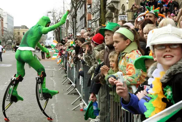 Zielony ludek na szczudłach podczas parady. Gdzie kupić piwo irlandzkie zielone? Może na festynie!
