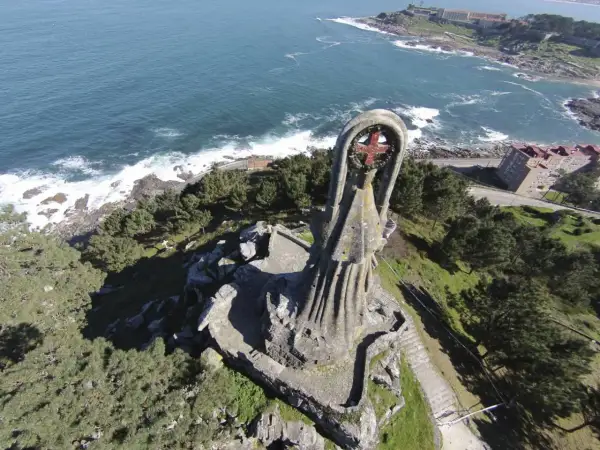 La Virgen de la Roca, una imponente estatua de piedra, vigila el mar azul desde un acantilado verde.