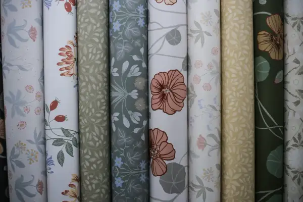 Rullar med vackra tapeter i olika mönster, inspirerade av naturen. Här finns blommor, blad och bär i harmoniska färger. En av tapeterna visar ett mönster av Hanna Wendelbo.