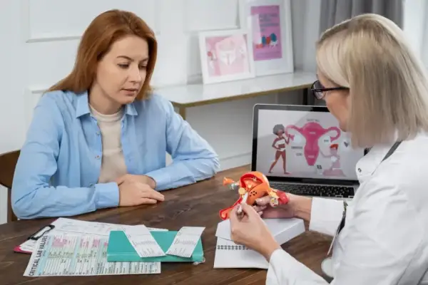 Lekarka wyjaśnia pacjentce model anatomiczny, omawiając objawy i leczenie adenomiozy.