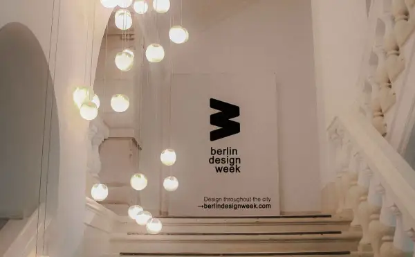 Eine Treppe mit Hängeleuchten und einem Banner für die **Berlin Design Week**.