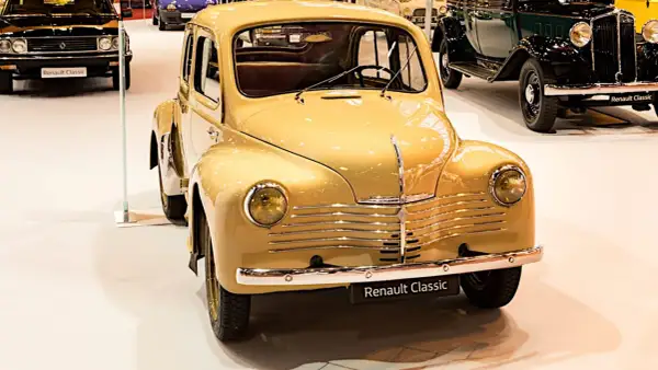 En gul, klassisk Renault 4CV står i förgrunden, en av många gamla Renault modeller på utställningen.