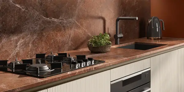 Piano cottura a gas su top in marmo rosso, con lavello nero, rubinetto moderno e bollitore Smeg. Le cucine con pavimento cotto hanno un fascino rustico.