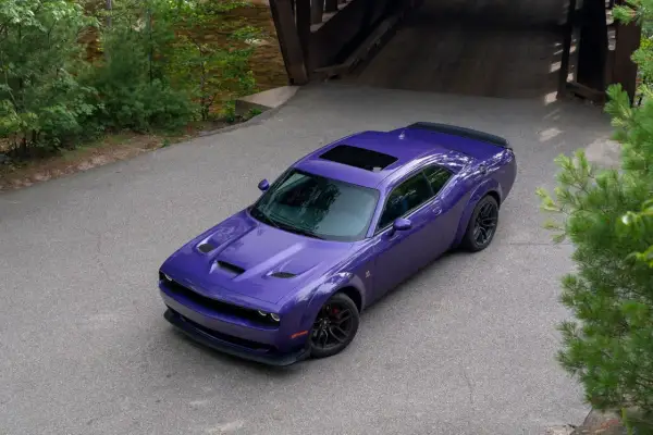 Fioletowy Dodge Challenger z czarnym spojlerem i szyberdachem, idealny na letnie przejażdżki. Sprawdź dodge challenger cena!