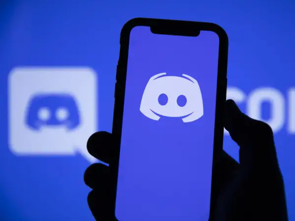 Dłoń trzyma smartfon z logo Discord. Aplikacja ta służy do komunikacji, więc jeśli zastanawiasz się "discord co to", to właśnie ją widzisz.