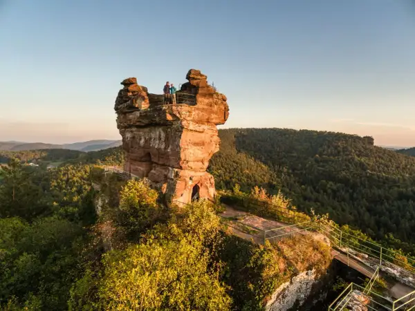 Dwie osoby stoją na szczycie skalnej wieży, podziwiając malownicze góry w zachodnich Niemczech.