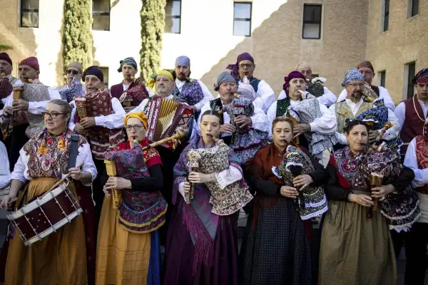 Grupo de gaiteros y músicos celebran el día San Jorge Zaragoza, con trajes tradicionales y diversos instrumentos.
