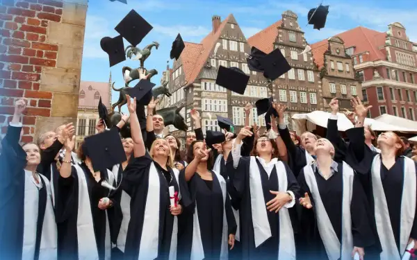 Absolventen der Apollon Hochschule werfen ihre Hüte in die Luft. Tolle Erfahrungen und ein erfolgreicher Abschluss!