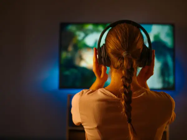 Dziewczyna w słuchawkach zanurzona w świecie filmu, gdzie muzyka buduje nastrój.