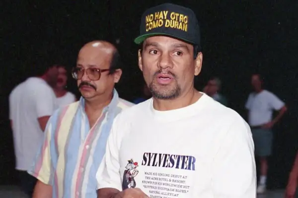 Roberto Duran reach, wearing a cap that says "No Hay Otro Como Duran." He's in a white t-shirt with "Sylvester" printed on it.