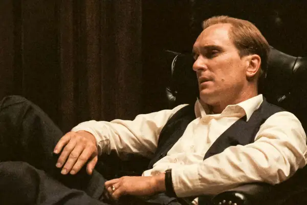 Robert Duvall jako Tom Hagen w fotelu, zamyślony, w białej koszuli i kamizelce.