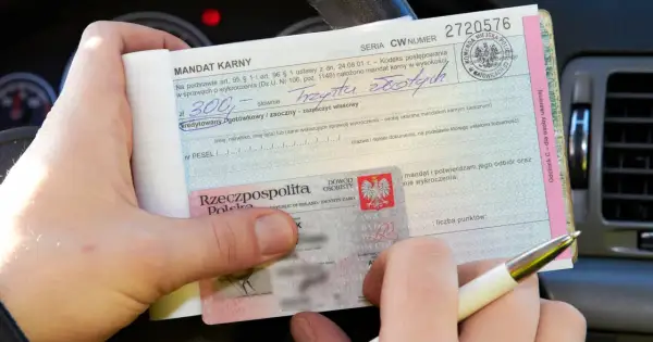 Ręka trzyma mandat karny na 300 zł, wystawiony za parkowanie na zakazie. Obok dowód osobisty.