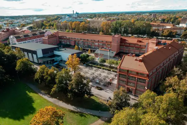 Luftfoto över Virginska gymnasiet med sina tegelbyggnader och en stor cykelparkering. Hösten färgar träden gyllene.