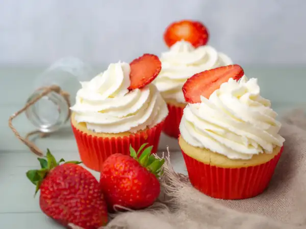 Erdbeer Cupcakes mit weißer Creme und frischen Erdbeeren, dekoriert mit Erdbeerscheiben.