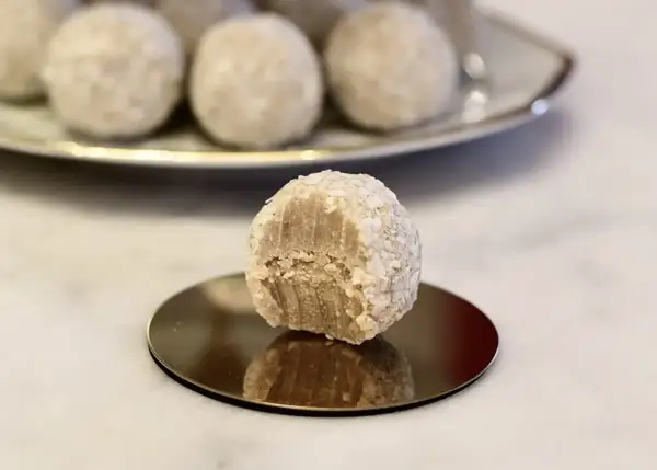 En bit tagen ur en av de fluffiga vita chokladbollarna, som är rullade i kokosflingor.