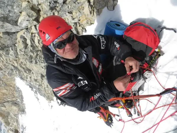 Alpinista w kasku i okularach, który nie ma lęku wysokości, przygotowuje sprzęt na dachu świata.
