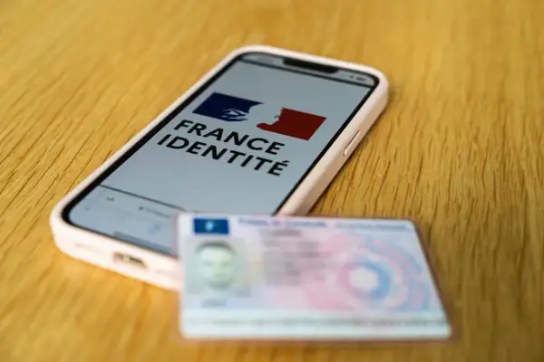 Un smartphone affiche "France Identité", à côté d'une carte d'identité physique. Le futur permis sur téléphone est en préparation.
