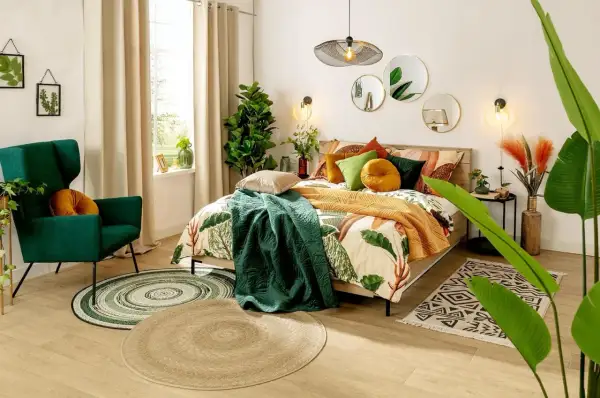 Sypialnia boho inspiracje: łóżko z pościelą w liście, zielony fotel, dywany i rośliny tworzą przytulną atmosferę.