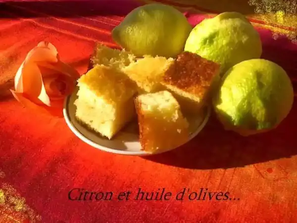 Gâteau au citron et à l'huile d'olive, une recette gâteau simple et délicieuse. Des parts de gâteau moelleux côtoient des citrons frais et une rose orangée sur un fond rouge.