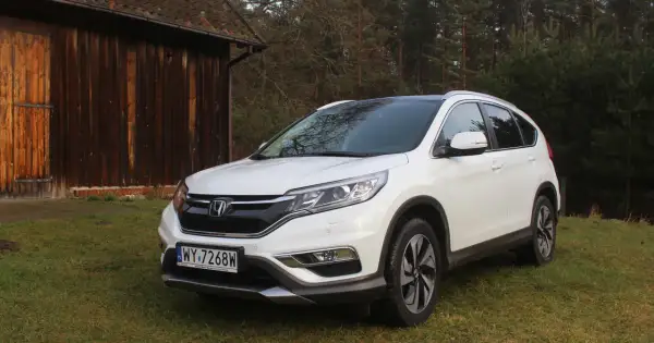Biały Honda CR-V 2.0 benzyna zaparkowany na trawie obok drewnianej stodoły.