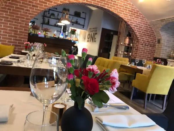 Stolik w jednej z klimatycznych restauracji Lublin. Kwiaty, kieliszki i żółte fotele tworzą przytulną atmosferę.