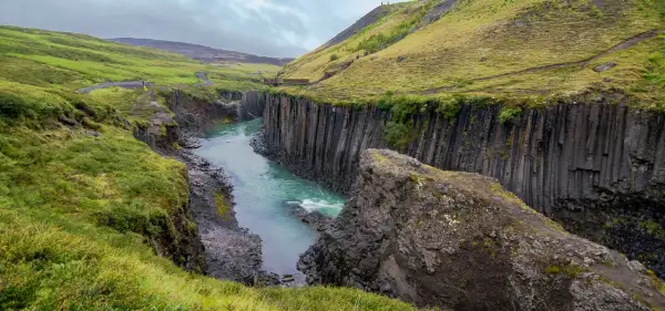 Un río turquesa serpentea entre cañones de basalto en Islandia, evocando la majestuosidad de los fiordos islandeses.