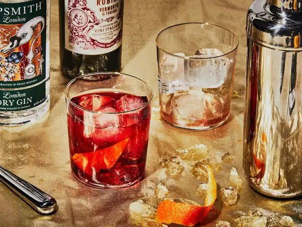Zutaten für einen Negroni: Gin, roter Wermut und Campari. Serviert mit Eis und Orangenzeste.