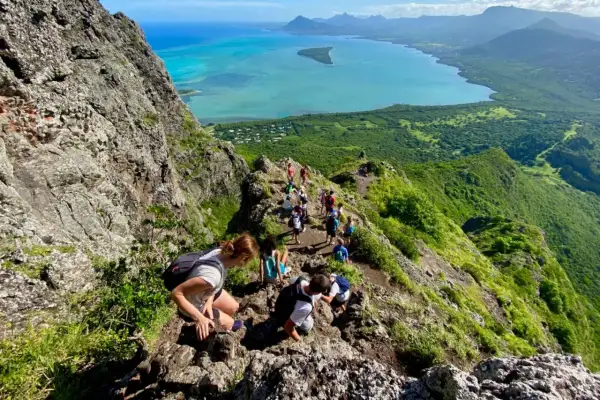 Wanderer erklimmen den Le Morne Brabant, eine atemberaubende Bergformation mit Blick auf das türkisfarbene Meer und üppige grüne Landschaften.