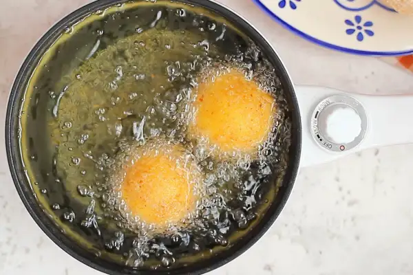Arancini di riso dorati friggono nell'olio bollente, creando un profumo invitante.